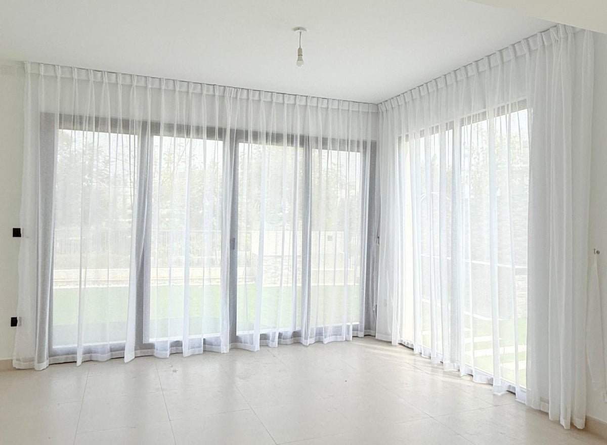 Sheer curtains on a ceiling track in an empty new villa