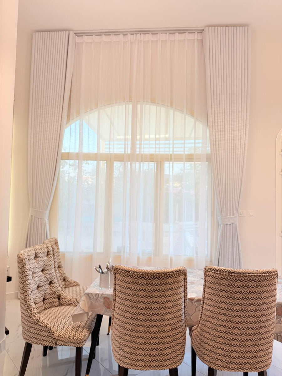 White sheer and side curtains at an arched window above a dining table