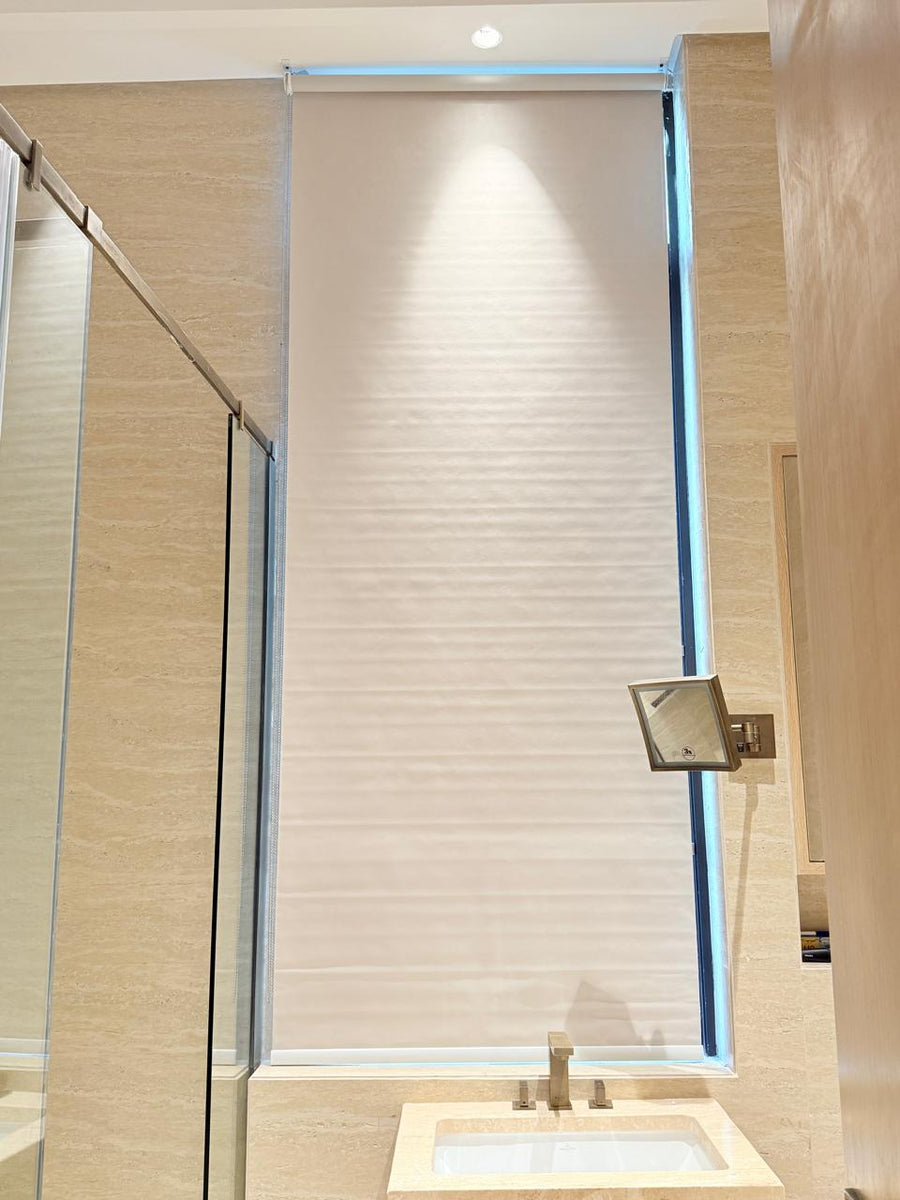 Roller blind lowered over a bathroom window above a stone basin