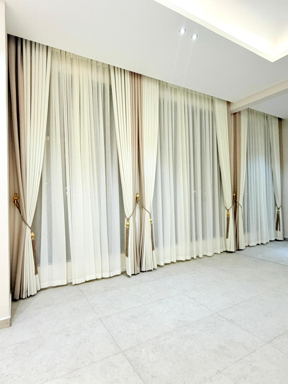 Cream curtains in a spacious living room with cove lighting