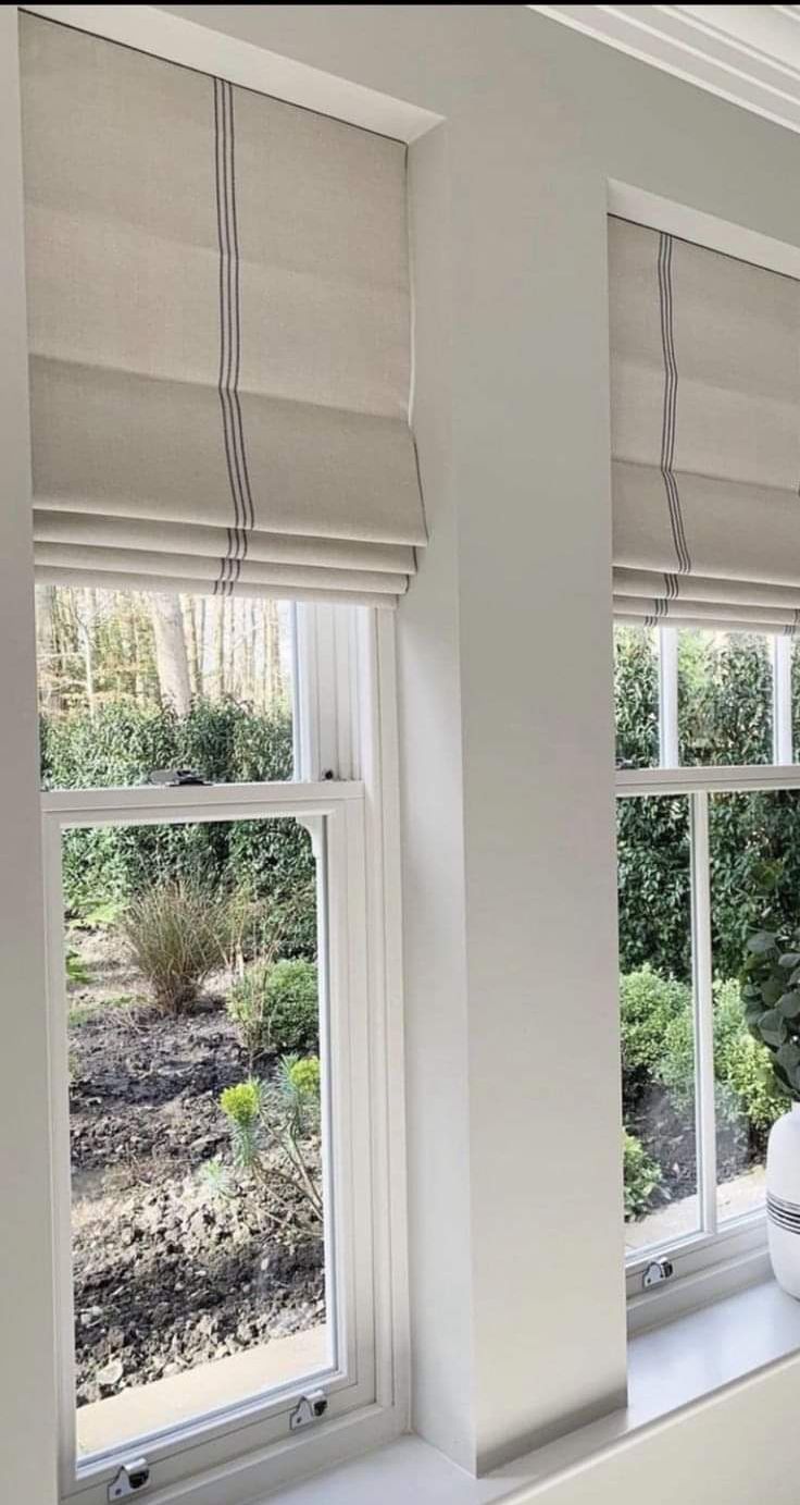 Cream roman blinds with a contrast pinstripe, stacked above two garden-facing sash windows